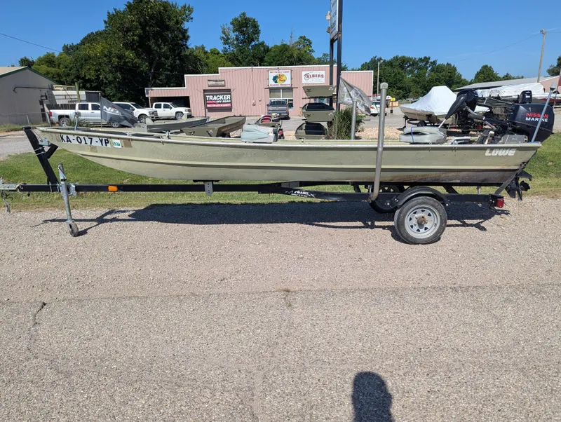 Slide: The Image of 1983 Lowe 16 Lake Jon boat on trailer, parked outdoors in a lot. - 2
