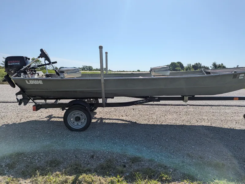 Slide: The Image of 1983 Lowe 16 Lake Jon boat on trailer with Nissan Marine motor, parked outdoors. - 6