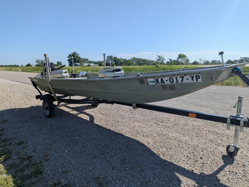 Slide: The Image of 1983 Lowe 16 Lake Jon boat on trailer, parked on gravel road under clear blue sky. - 7