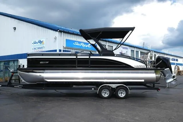 Slide: The Image of 2026 Harris Solstice 250 pontoon boat on trailer, parked outside dealership. - 2