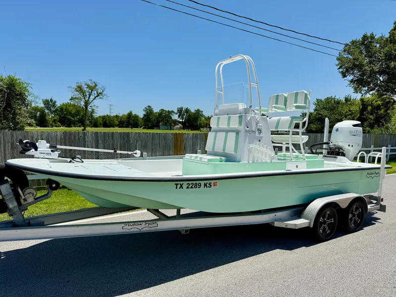 The Image of 2023 Shallow Sport 24 Sport boat on trailer, mint green hull, outdoor setting. - 1