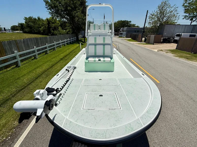 Slide: The Image of 2023 Shallow Sport 24 Sport boat on road, featuring spacious deck and trolling motor. - 6