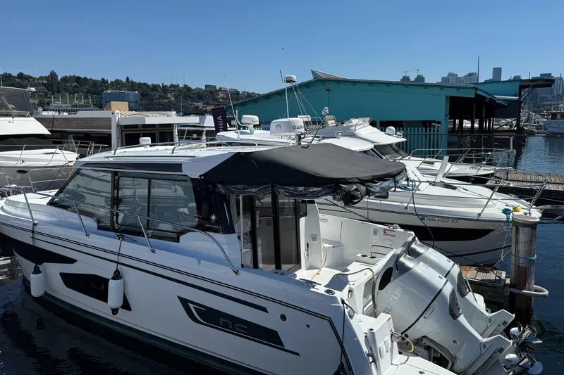Slide: The Image of 2022 Jeanneau NC 1095 Coupe docked at a marina under clear blue skies. - 18