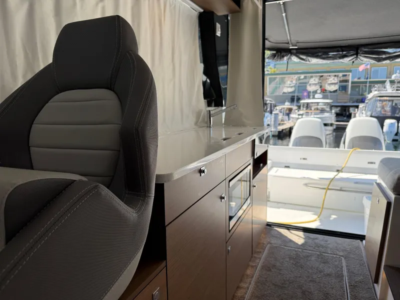 Slide: The Image of Interior of 2022 Jeanneau NC 1095 Coupe, featuring modern seating and kitchenette with marina view. - 3