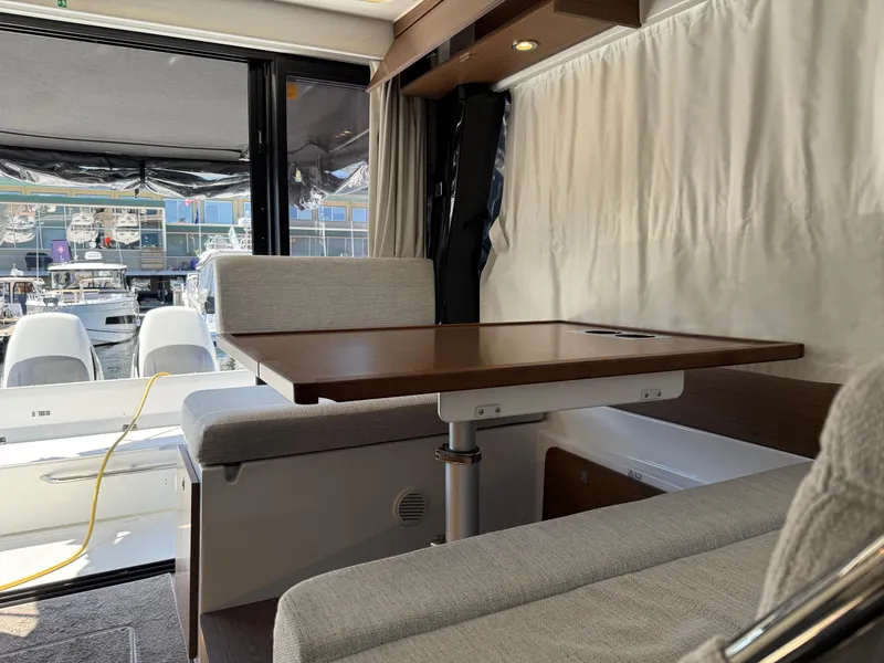 Slide: The Image of Interior of 2022 Jeanneau NC 1095 Coupe with dining area and marina view. - 4