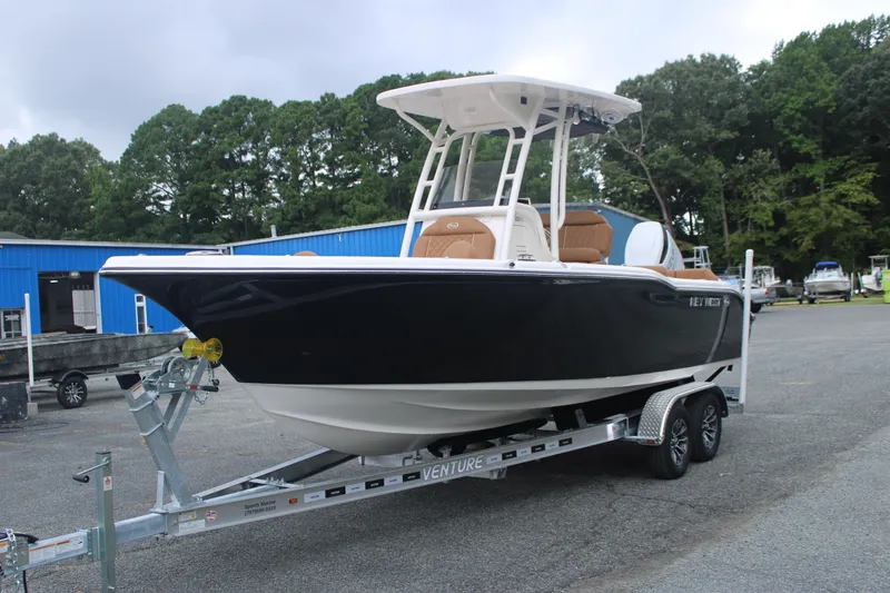 Slide: The Image of 2026 Key West 239 FS boat on trailer, parked outdoors near blue building. - 2