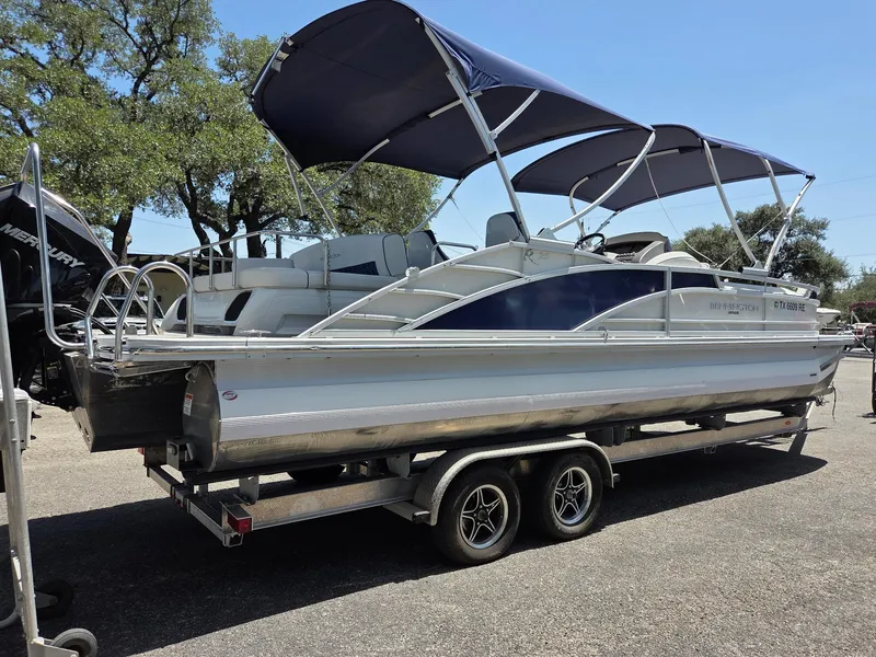 Slide: The Image of 2023 Bennington 25RTSB pontoon boat on trailer, featuring dual bimini tops. - 1