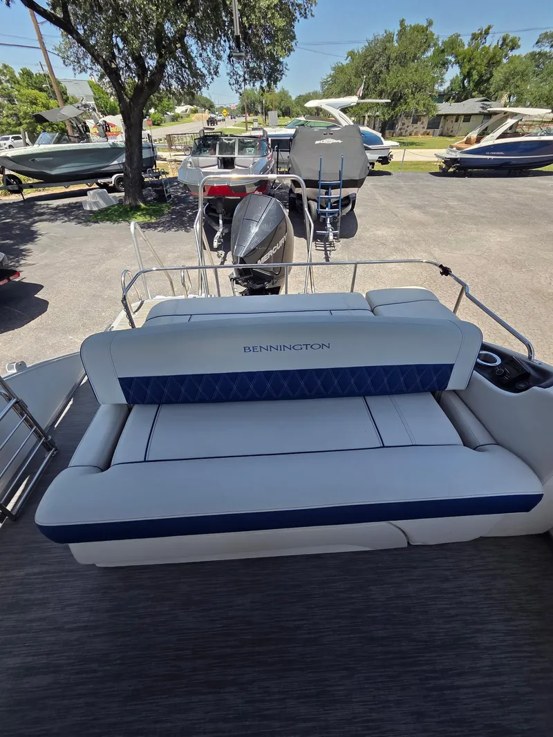 Slide: The Image of 2023 Bennington 25RTSB boat with cushioned seating, parked outdoors. - 7