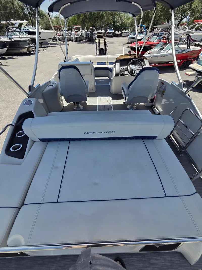 Slide: The Image of 2023 Bennington 25RTSB pontoon boat interior with seating and helm, parked in marina. - 8