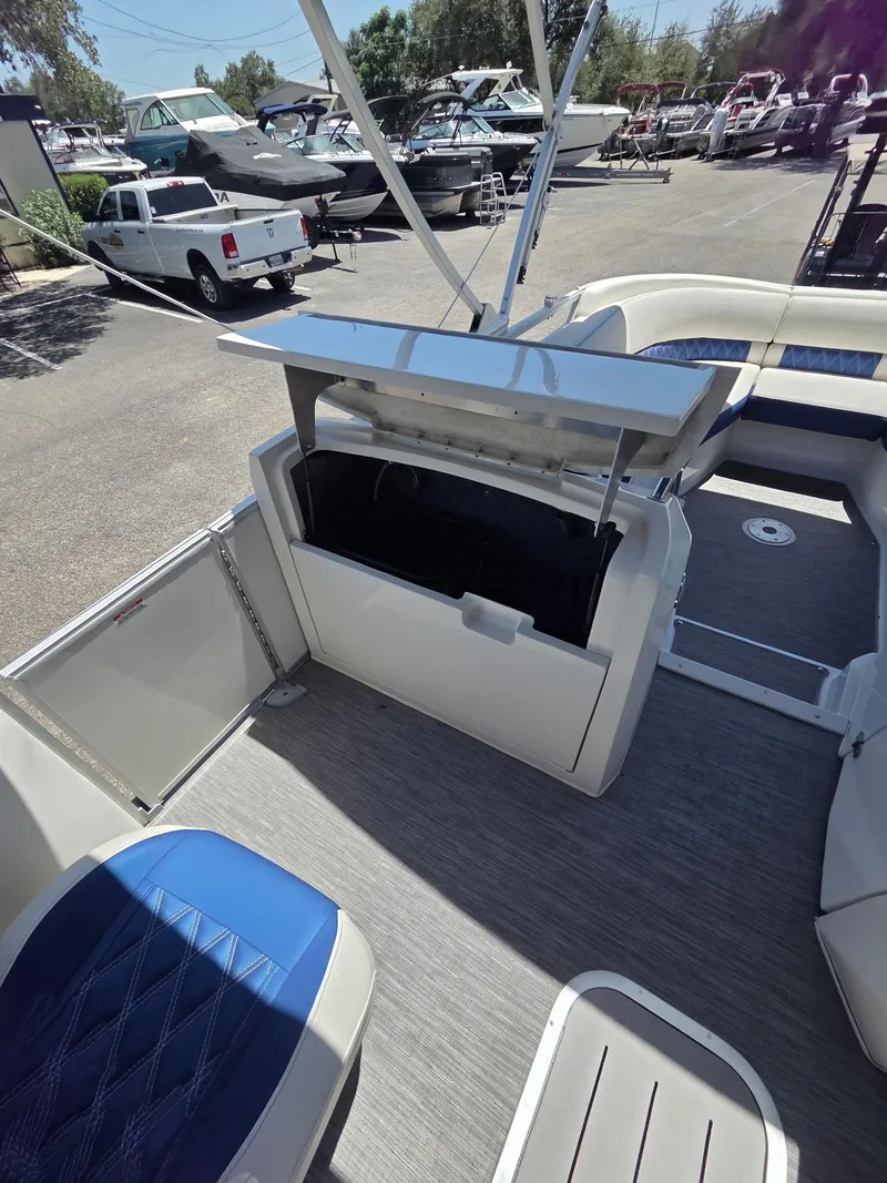Slide: The Image of 2023 Bennington 25RTSB pontoon boat interior with open storage compartment and blue seating. - 9