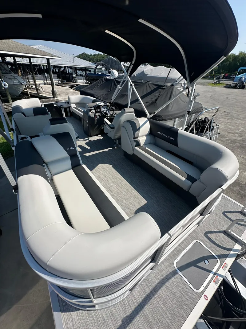 Slide: The Image of 2025 Bennington 22 SSRSE pontoon boat with spacious seating and canopy at a marina. - 9