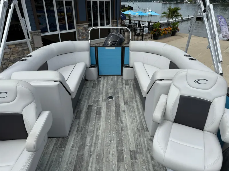 Slide: The Image of 2022 Crest 220 boat interior with gray seating and wood-style flooring, docked by a lakeside. - 23