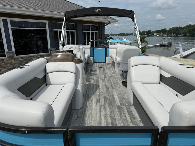 Slide: The Image of 2022 Crest 220 pontoon boat with white seating, docked by a lakeside building. - 9