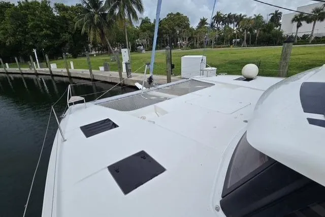 Slide: The Image of 2022 Fountaine Pajot Tanna 47 catamaran docked near lush greenery and calm waters. - 6