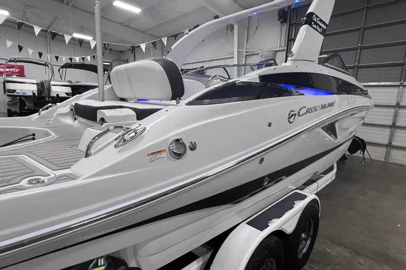 Slide: The Image of 2020 Crownline E225 XS boat in showroom, sleek design, white exterior, modern features. - 45