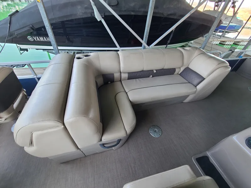 Slide: The Image of 2021 Sun Tracker 22 Fishin Barge interior with beige seating and cup holders. - 11
