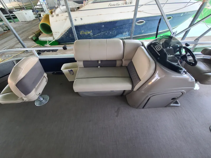 Slide: The Image of 2021 Sun Tracker 22 Fishin Barge interior with beige seating and steering console. - 8