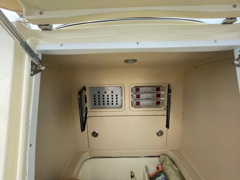 Slide: The Image of 2015 Chris-Craft Catalina 23 storage compartment with organized shelves and secure latch. - 21