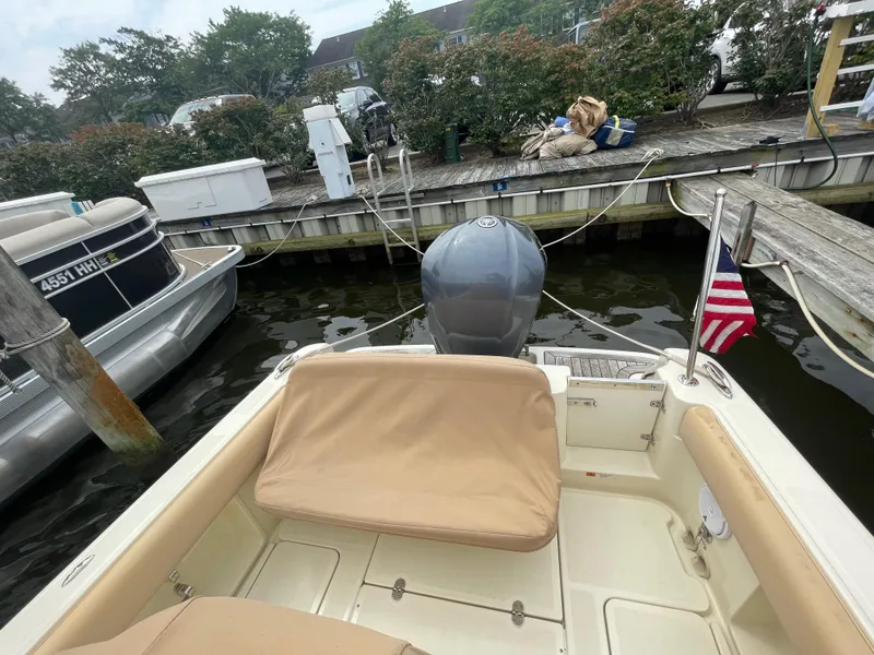 Slide: The Image of 2015 Chris-Craft Catalina 23 docked, featuring beige seating and an American flag. - 5