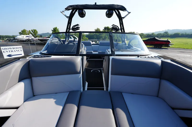 Slide: The Image of 2025 Moomba Max boat interior with gray seating, showroom entrance sign, and scenic background. - 6
