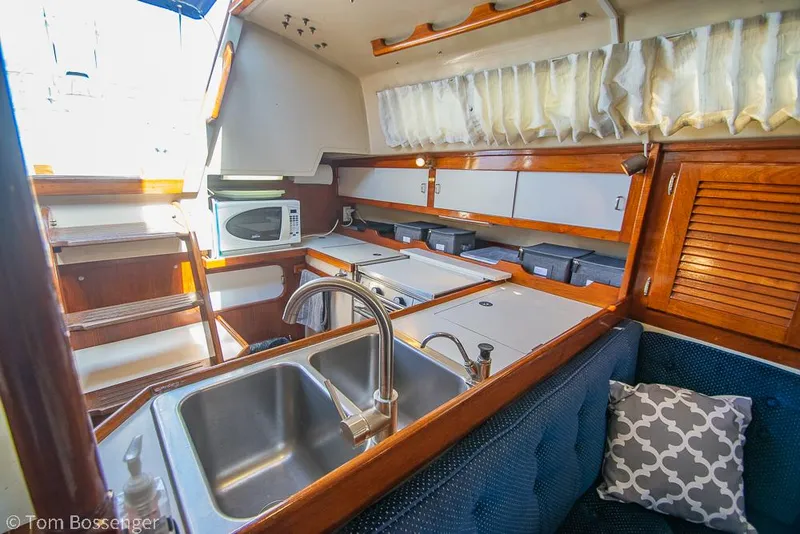 Slide: The Image of Interior of 1987 Catalina 36 sailboat kitchen with sink, microwave, and wooden cabinetry. - 12
