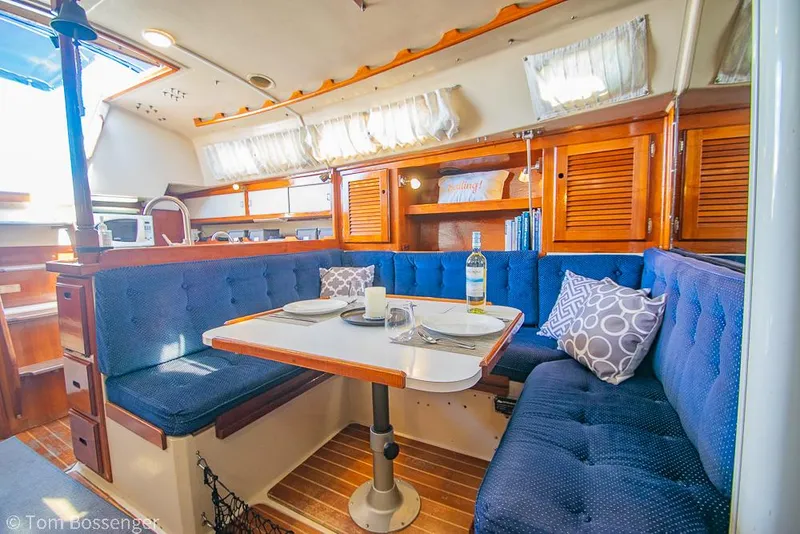 Slide: The Image of Cozy interior of a 1987 Catalina 36 sailboat with blue seating and dining area. - 17