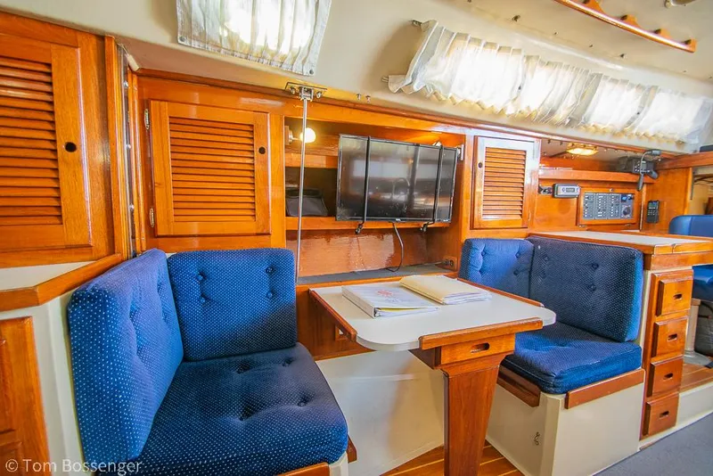 Slide: The Image of Interior of 1987 Catalina 36 sailboat with blue cushioned seating and wooden cabinetry. - 19