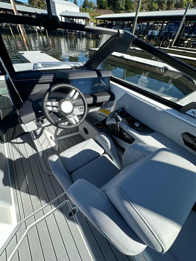 Slide: The Image of 2025 Nautique Super Air Nautique G23 cockpit with modern steering and controls, dockside view. - 16
