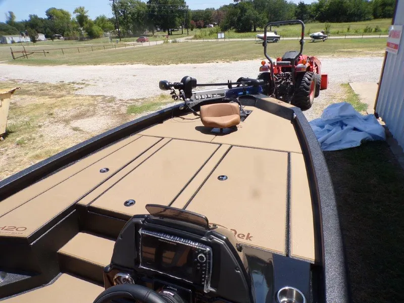Slide: The Image of 2026 Xpress H20 Bass boat with tan deck, parked near a red tractor. - 1