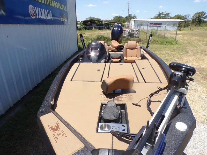 Slide: The Image of 2026 Xpress H20 Bass boat with tan deck and seating, parked outdoors. - 16