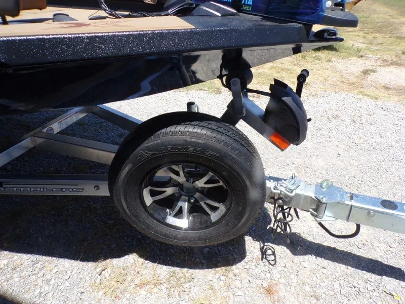 Slide: The Image of 2026 Xpress H20 Bass boat trailer with black wheel on gravel surface. - 27