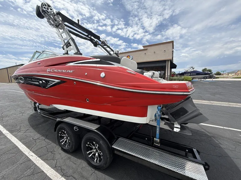 Slide: The Image of 2022 Crownline Eclipse E235 SURF boat in vibrant red on a trailer, parked outdoors. - 3