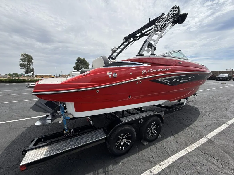 Slide: The Image of 2022 Crownline Eclipse E235 SURF boat in vibrant red on a trailer, parked outdoors. - 5