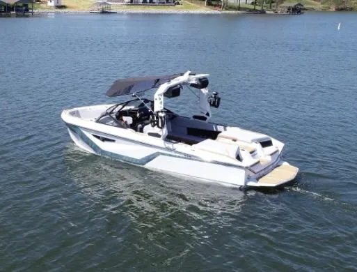 Slide: The Image of 2025 Nautique Super Air Nautique S23 boat on a serene lake. - 1