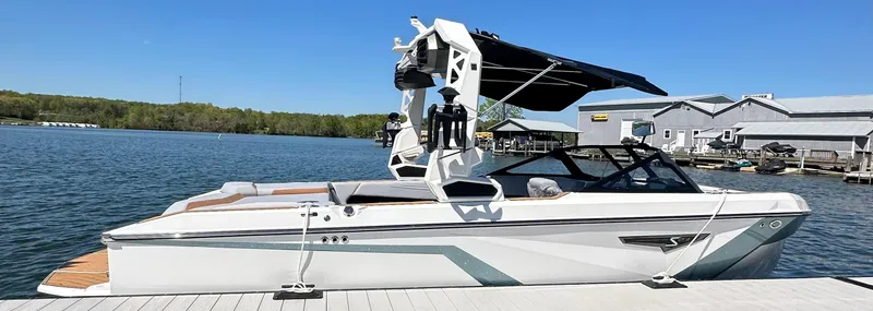 Slide: The Image of 2025 Nautique Super Air Nautique S23 boat docked on a sunny lake. - 10