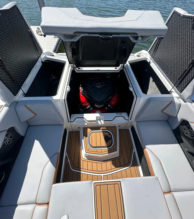 Slide: The Image of 2025 Nautique Super Air Nautique S23 boat interior with open storage compartments and engine view. - 16