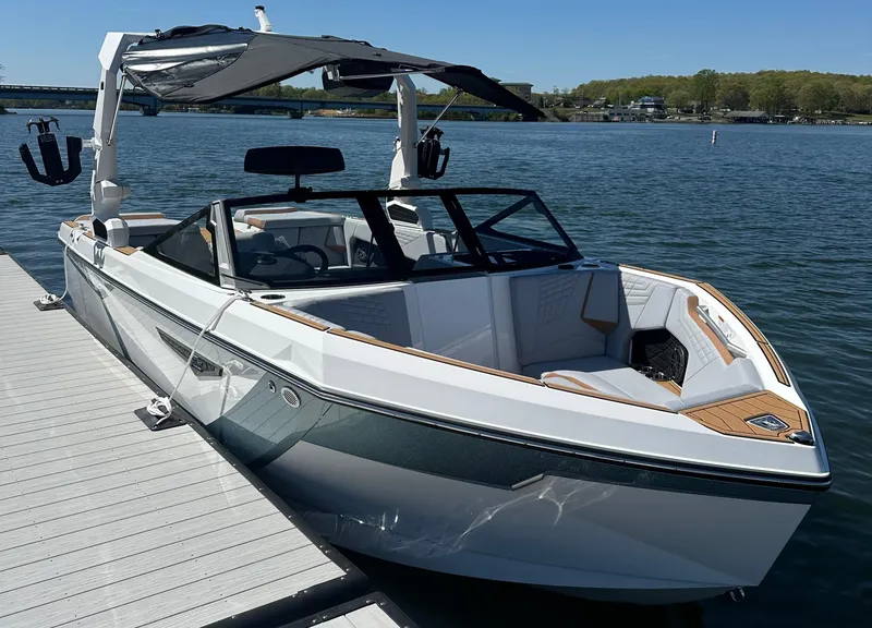 Slide: The Image of 2025 Nautique Super Air Nautique S23 boat docked on a sunny lake. - 9