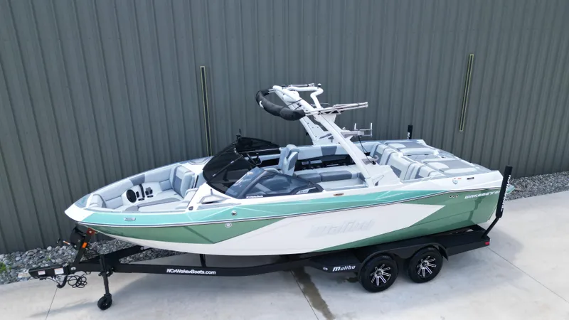 Slide: The Image of 2025 Malibu Wakesetter 23 LSV boat on trailer, green and white design, parked outdoors. - 8