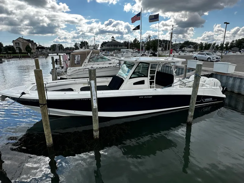 Slide: The Image of 2014 Boston Whaler 370 Outrage docked at a marina with flags in the background. - 5