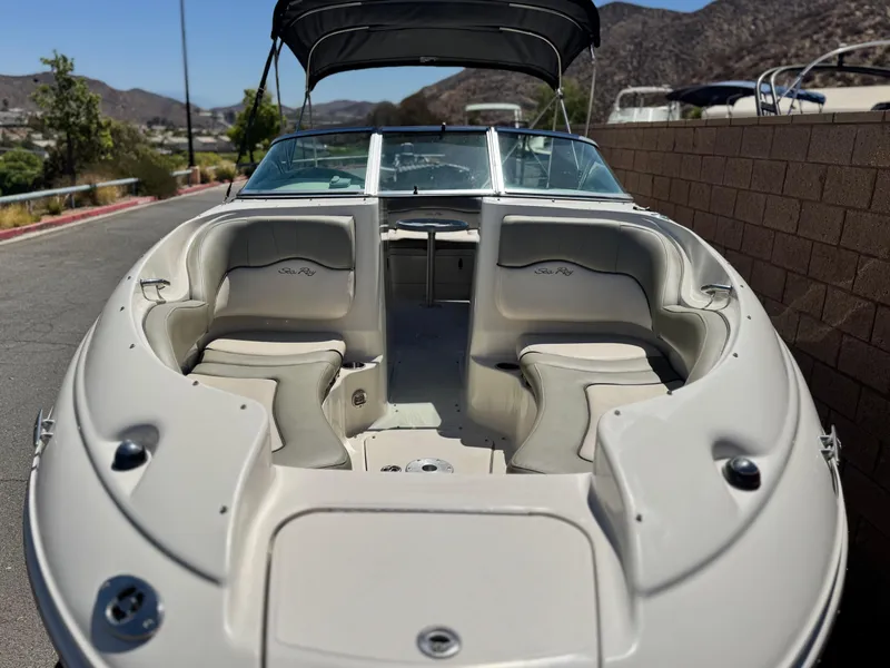 Slide: The Image of 2005 Sea Ray 220 Sundeck boat with spacious seating and canopy, parked outdoors. - 10