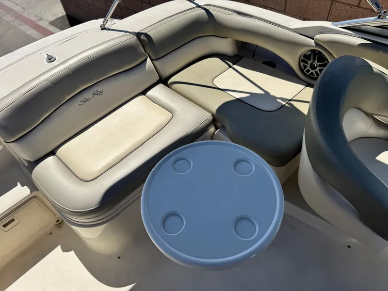 Slide: The Image of 2005 Sea Ray 220 Sundeck interior with cushioned seating and round table. - 18