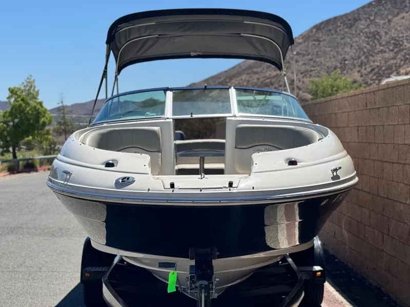 Slide: The Image of 2005 Sea Ray 220 Sundeck boat with canopy, parked on a trailer, mountain backdrop. - 2