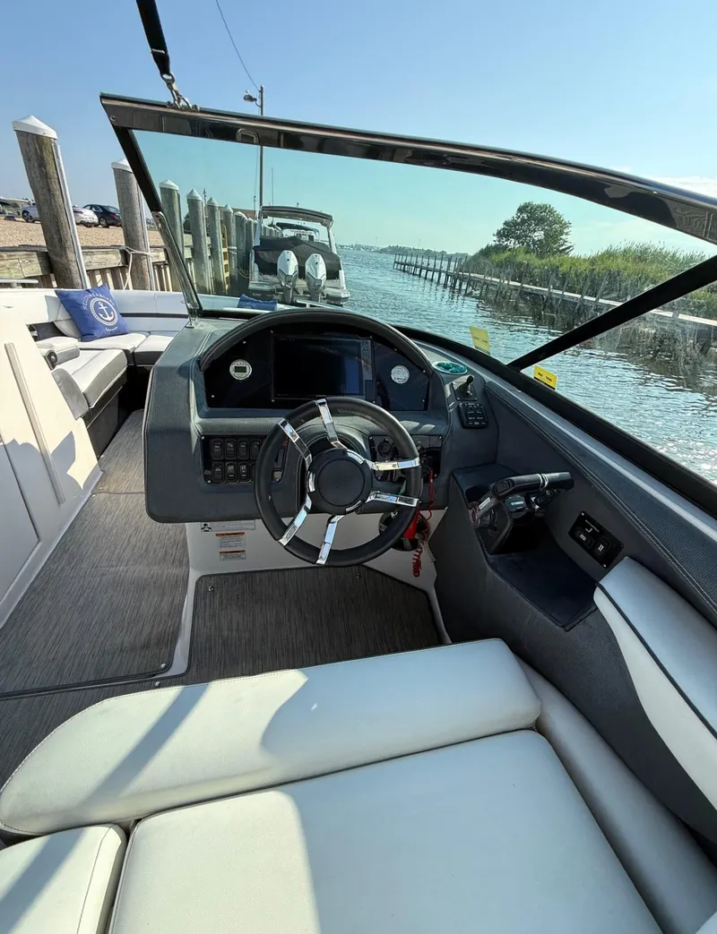 Slide: The Image of 2017 Regal 29 OBX boat cockpit with steering wheel and dashboard, docked by the water. - 10