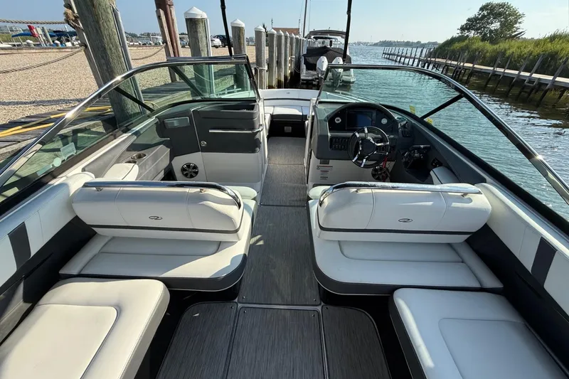 Slide: The Image of 2017 Regal 29 OBX boat interior with sleek seating and modern dashboard at a dock. - 7