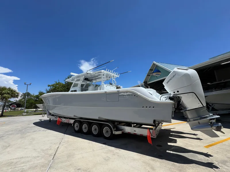 Slide: The Image of 2026 Invincible 46 Catamaran with Mercury engines on a trailer under clear blue sky. - 16
