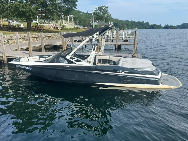 Slide: The Image of 2013 Axis A20 boat docked on a serene lake with lush greenery. - 10