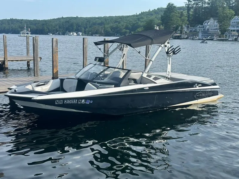 Slide: The Image of 2013 Axis A20 boat docked on a serene lake with lush green surroundings. - 11