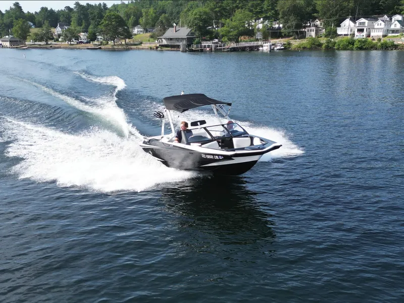 Slide: The Image of 2013 Axis A20 boat cruising on a scenic lake with waterfront homes. - 19