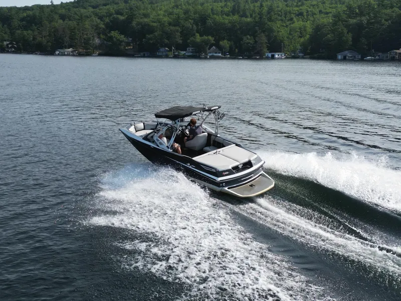 Slide: The Image of 2013 Axis A20 boat cruising on a lake with lush green forest backdrop. - 21