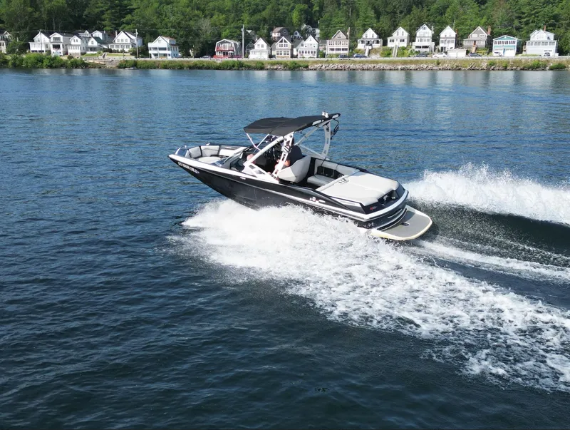 Slide: The Image of 2013 Axis A20 boat cruising on a lake with houses in the background. - 24